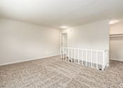 Thumbnail 5 of 27 - Empty room with carpeted floor and white railings.