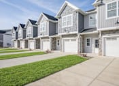 Thumbnail 6 of 15 - A row of houses with garages and driveways.