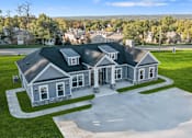 Thumbnail 1 of 43 - A large house with a grey roof and a driveway in front.