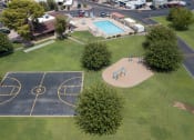 Thumbnail 6 of 13 - Bird's eye view of Belaire Manor, basketball court, grass area, trees, playground equipment and swimming pool