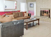 Thumbnail 1 of 10 - A living room with a grey couch and a fireplace.