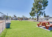 Thumbnail 7 of 10 - A red picnic table sits on a concrete slab in a grassy park.