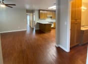 Thumbnail 9 of 11 - an empty living room with wood floors and a kitchen