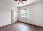 Thumbnail 16 of 16 - A room with a ceiling fan and a window with a view of trees.