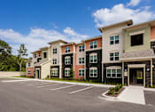 Thumbnail 3 of 25 - A row of modern townhouses with a parking lot in front.