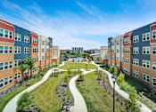 Thumbnail 1 of 14 - A view of a courtyard surrounded by buildings with a bicycle parked on the grass.