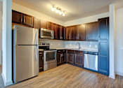 Thumbnail 5 of 14 - A kitchen with dark wood cabinets and stainless steel appliances.