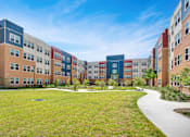 Thumbnail 11 of 14 - A large grassy area in front of a row of buildings.