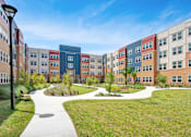 Thumbnail 2 of 14 - A modern building complex with a walkway in the foreground.