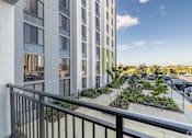 Thumbnail 5 of 9 - A balcony overlooks a parking lot and a building with a green roof.