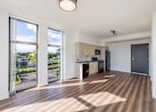 Thumbnail 6 of 9 - A spacious kitchen and living room with wooden flooring and large windows.