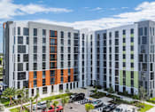 Thumbnail 4 of 9 - A modern multi-story building with a parking lot in front.