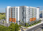 Thumbnail 2 of 9 - A modern multi-story building with orange and grey accents.