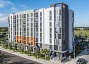 Thumbnail 1 of 9 - A modern multi-story building with a sign that reads "NOW LOW LEASING".