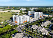 Thumbnail 3 of 9 - A large building with a lot of windows is surrounded by other buildings and trees.