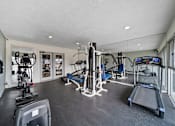 Thumbnail 9 of 14 - A gym with a variety of equipment including treadmills, weights, and exercise machines.