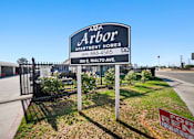 Thumbnail 1 of 12 - A sign for Arbor Apartment Homes is displayed in front of a fence.