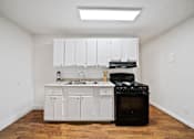 Thumbnail 7 of 12 - A kitchen with white cabinets and a black stove top oven.