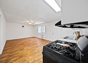 Thumbnail 6 of 12 - A kitchen with a black stove top oven and wooden flooring.