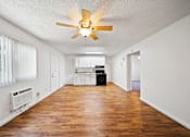 Thumbnail 5 of 12 - A room with a ceiling fan and wooden floors.