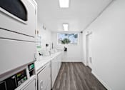 Thumbnail 6 of 9 - A long white hallway with a washing machine on the left.