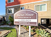 Thumbnail 2 of 8 - A sign for Burnet House Apartments is in front of a building.