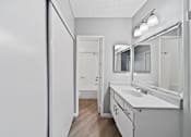 Thumbnail 19 of 23 - A white bathroom with a sink, mirror, and towel rack.