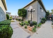 Thumbnail 3 of 23 - A street lamp stands on a brick base in front of a building.