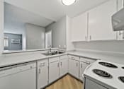 Thumbnail 17 of 23 - A white kitchen with a stove top oven.