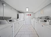 Thumbnail 20 of 23 - A row of white washing machines in a laundromat.