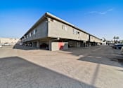 Thumbnail 11 of 23 - A concrete building with a parking lot in front.