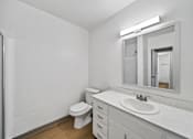 Thumbnail 22 of 22 - A white bathroom with a toilet, sink, and mirror.