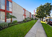 Thumbnail 8 of 22 - A long concrete walkway leads to a building with red trim.