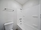 Thumbnail 20 of 21 - A white bathroom with a toilet, a bathtub, and a towel rack.