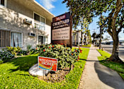 Thumbnail 1 of 21 - A sign for 16025 Courtyard Apartments is displayed in front of a building.