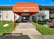 Thumbnail 2 of 21 - The entrance to Courtyard Apartments with a red sign on the right.