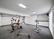 Thumbnail 11 of 21 - A gym with a variety of equipment including a stationary bike, a rowing machine, and a weight bench.