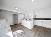 Thumbnail 18 of 21 - A white room with a white fridge and a white cupboard.