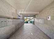 Thumbnail 12 of 21 - A long hallway with a row of lockers on the left and electrical boxes on the wall.