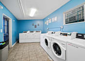 Thumbnail 6 of 8 - A row of white front load washing machines in a laundromat.