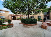 Thumbnail 12 of 23 - A courtyard with a tree and bushes in the middle surrounded by buildings.