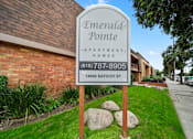 Thumbnail 1 of 23 - A sign for Emerald Pointe Apartment Homes stands in front of a brick building.