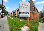 Thumbnail 4 of 23 - A sign for Emerald Pointe Apartment Homes stands in front of a building.
