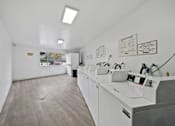 Thumbnail 23 of 23 - A clean, white-walled laundromat with multiple washing machines.