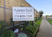 Thumbnail 1 of 9 - A sign for Fullerton Court Apartment Homes stands in front of a building.