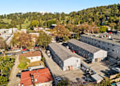 Thumbnail 2 of 5 - A large white building with a red roof is surrounded by other buildings and trees.