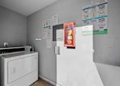 Thumbnail 4 of 5 - A white washing machine sits in a laundry room with a white dryer.