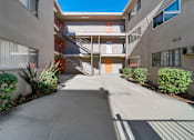 Thumbnail 8 of 9 - A concrete courtyard with a staircase leading to a building.