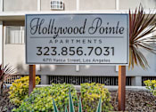 Thumbnail 6 of 9 - A sign for Hollywood Pointe Apartments stands in front of a building.