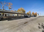 Thumbnail 5 of 5 - A parking lot with a building and trees in the background.